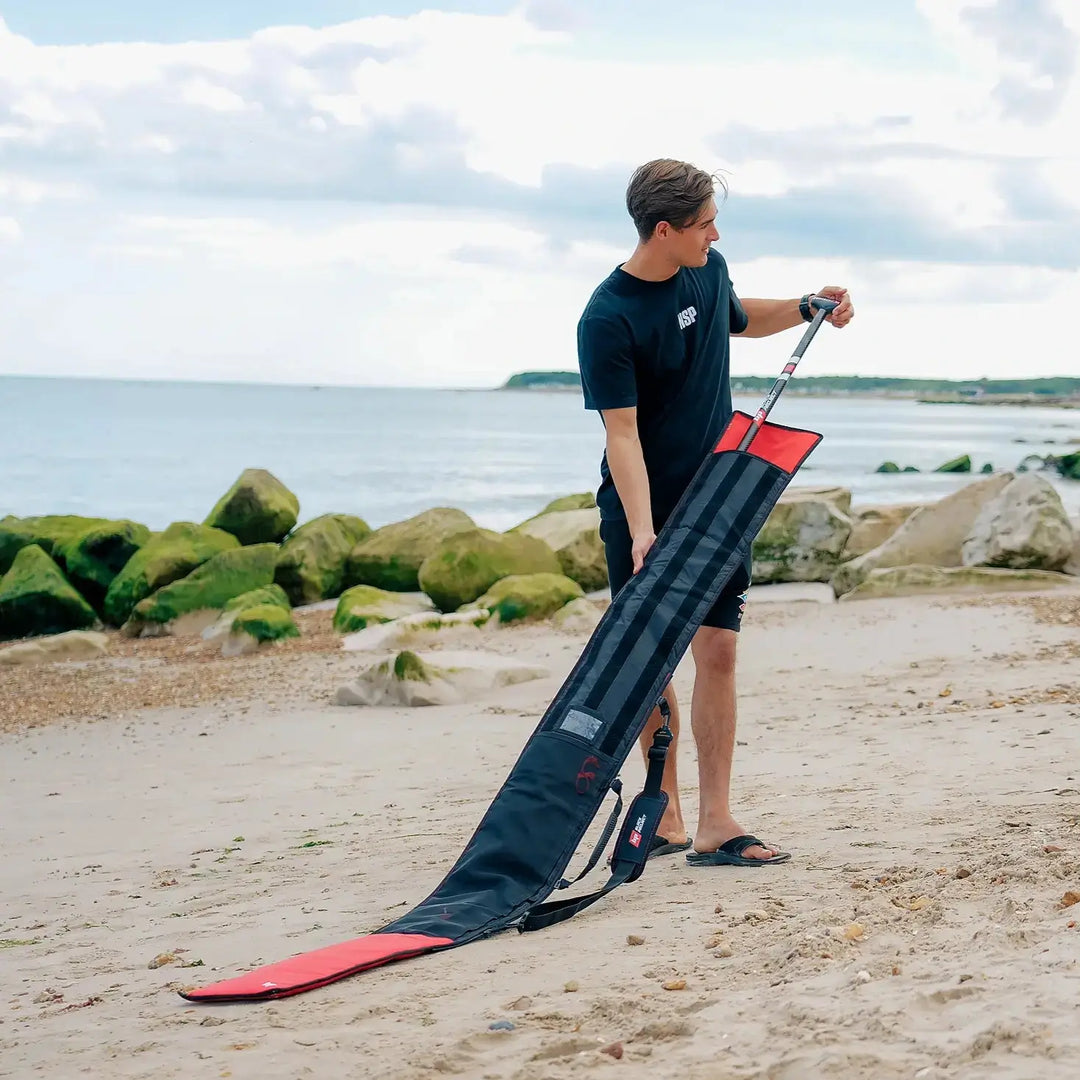 Image of person using the Black Project SUP Paddle Bag to store a Carbon SUP Paddle while on the beach.