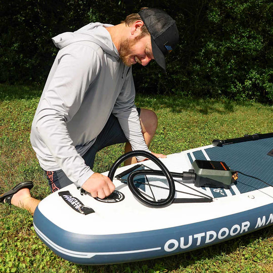 Man inflating an inflatable paddle board outdoors.