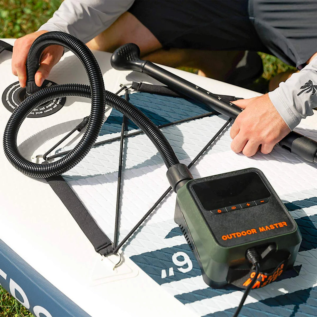 Person using an electric SUP pump on a paddleboard with 'Outdoor Master' branding.