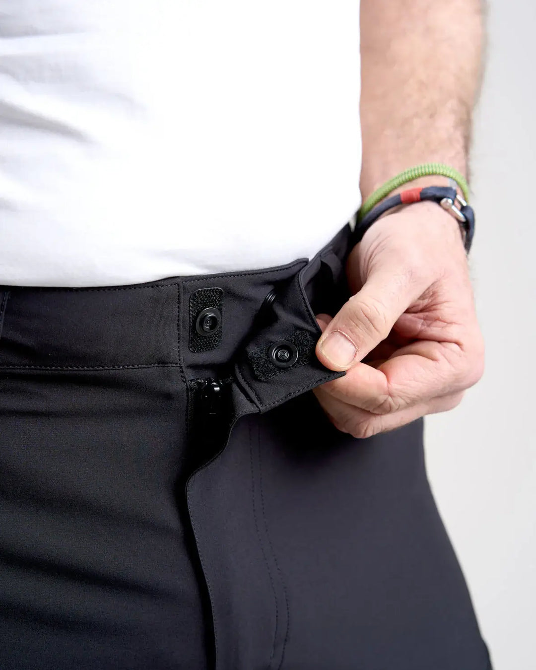 Studio image of a model wearing the black Rooster Technical Shorts 2.0 with a close up of the waist fastening on a white background.