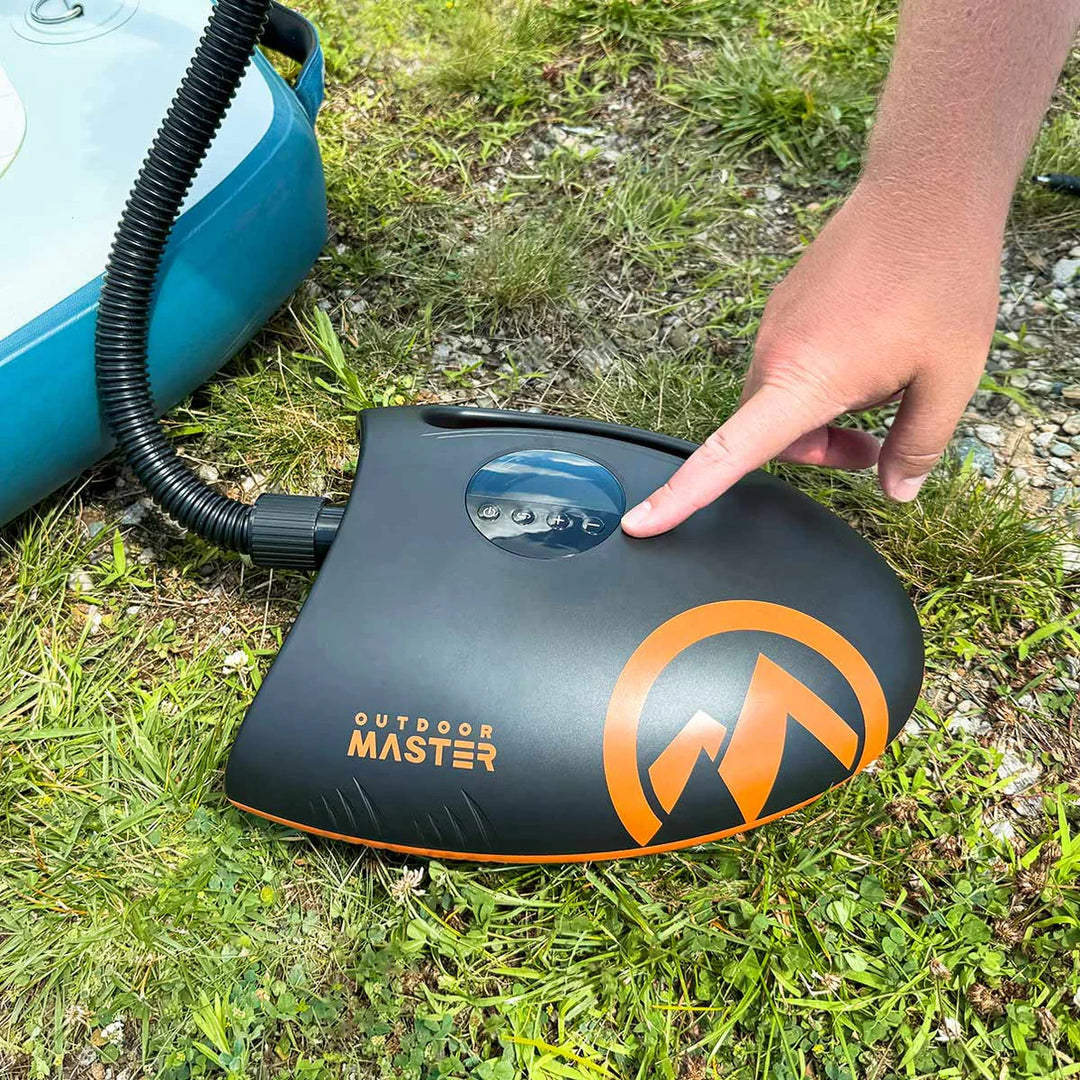 Hand pressing a button on an 'Outdoor Master' SUP pump on grass