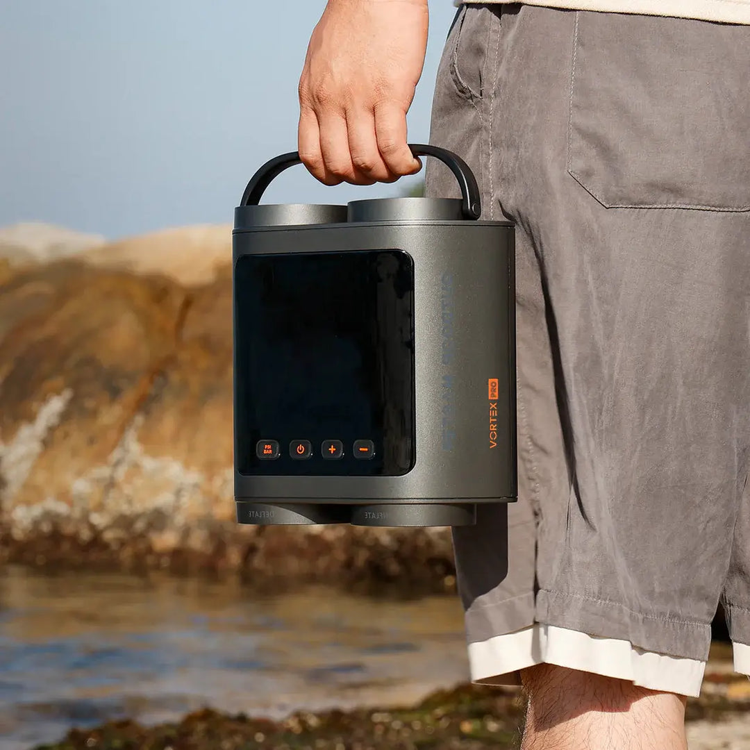 Person holding a portable SUP pump with a mountainous background