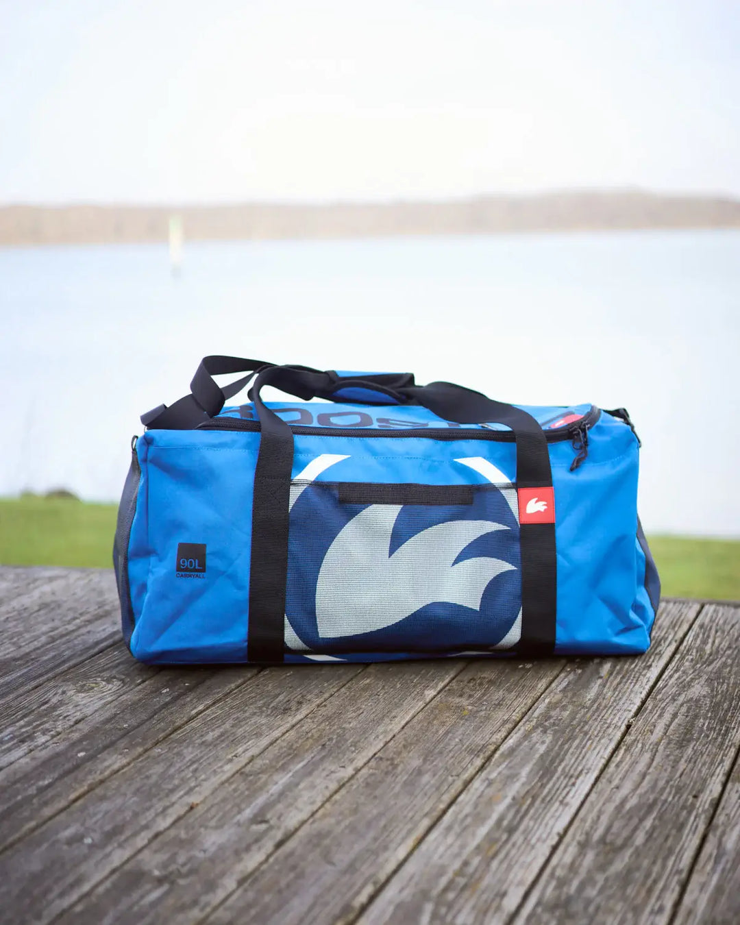 Blue duffel bag with a logo on a wooden surface