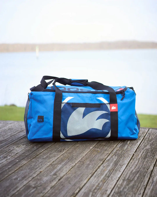 Blue duffel bag with a logo on a wooden surface