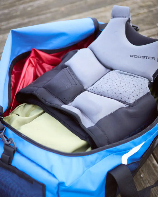 Grey and black buoyancy aid with 'Rooster' branding inside a blue sailing bag on a wooden surface.