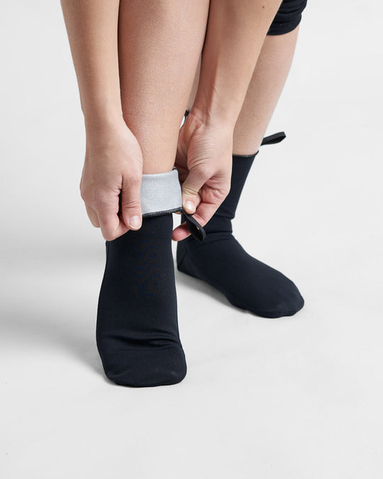 Black neoprene socks being folded down, designed for water activities.
