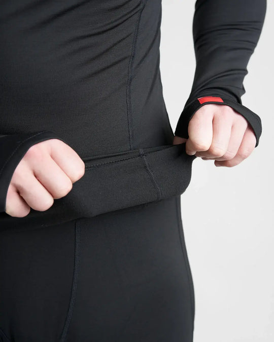 Person wearing a black long-sleeve PolyPro top with a red label on a light white background.