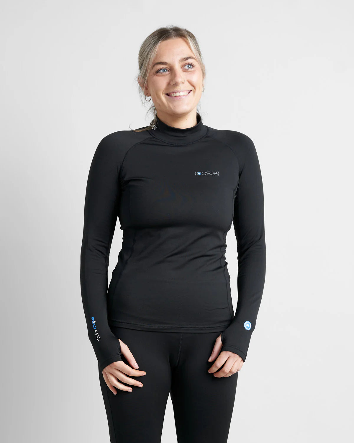 Person wearing a black long-sleeve hydrophobic base layer top with a logo on a light grey background.