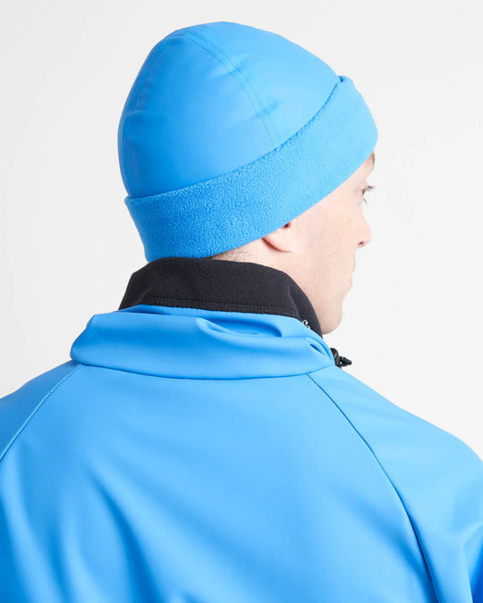Person wearing a blue sailing beanie and jacket on a light grey background.