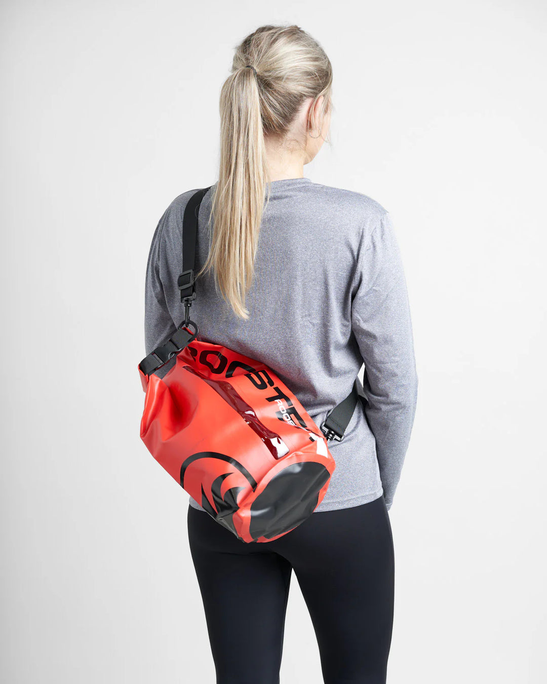 Person wearing a red and black watersports dry bag on a plain background.