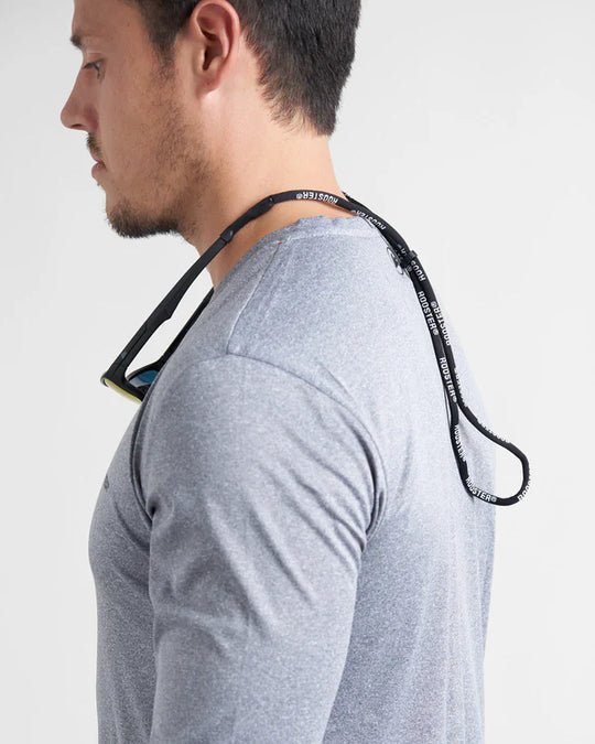 A person wearing sunglasses and a black strap designed to hold the glasses in place, displayed with glasses around neck.