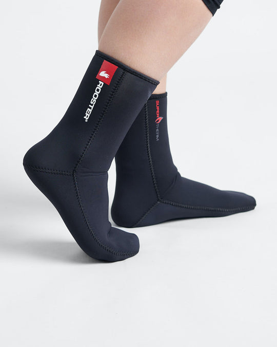 Studio image of model wearing black 4mm thick neoprene socks with a white and red Rooster logo.