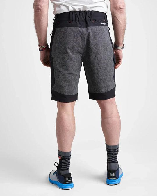 Studio image of a model wearing the black Rooster Technical Shorts 2.0 show the wear resistant material on the back on a white background.