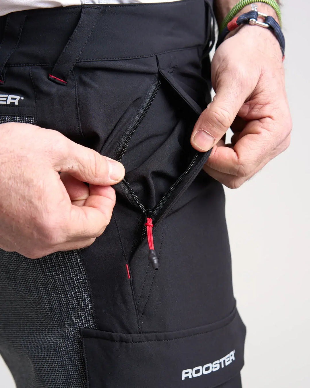 Studio image of a model wearing the black Rooster Technical Shorts 2.0 with a close up of the pocket opening on a white background.