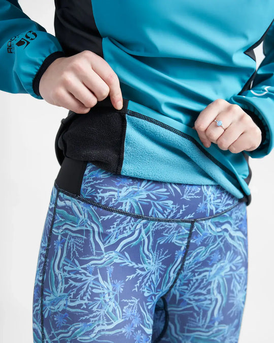 Person wearing a teal sailing top and blue patterned pants on a white background.