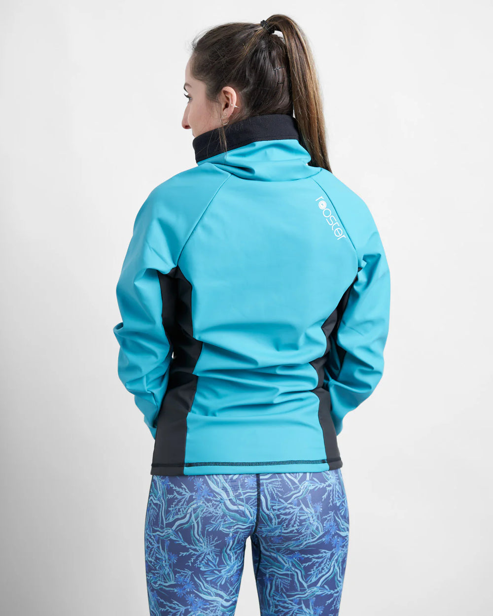 Person wearing a teal watersports top with a visible brand logo on a white background.