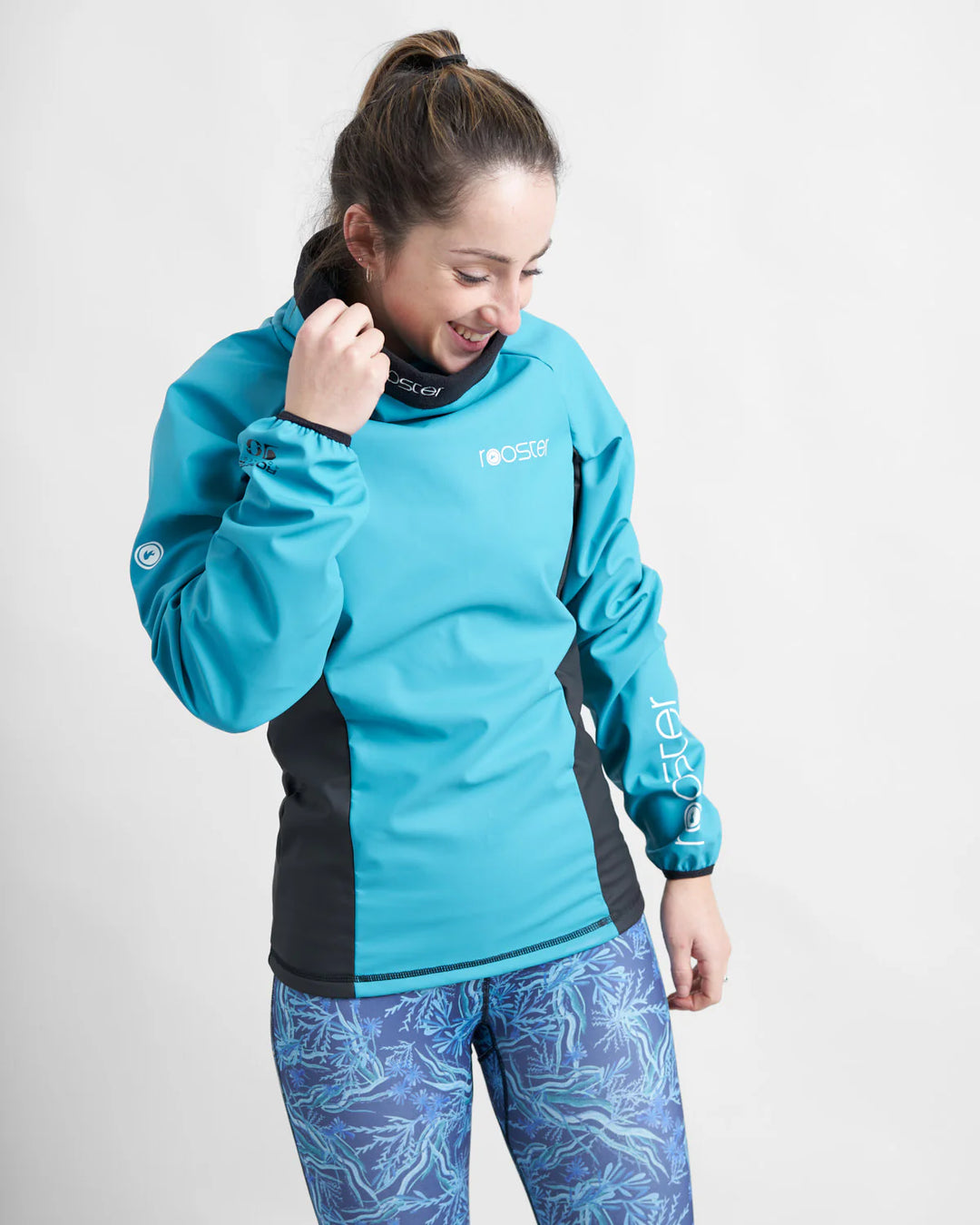 Woman wearing a teal Aquafleece top with black side panels on a white background.