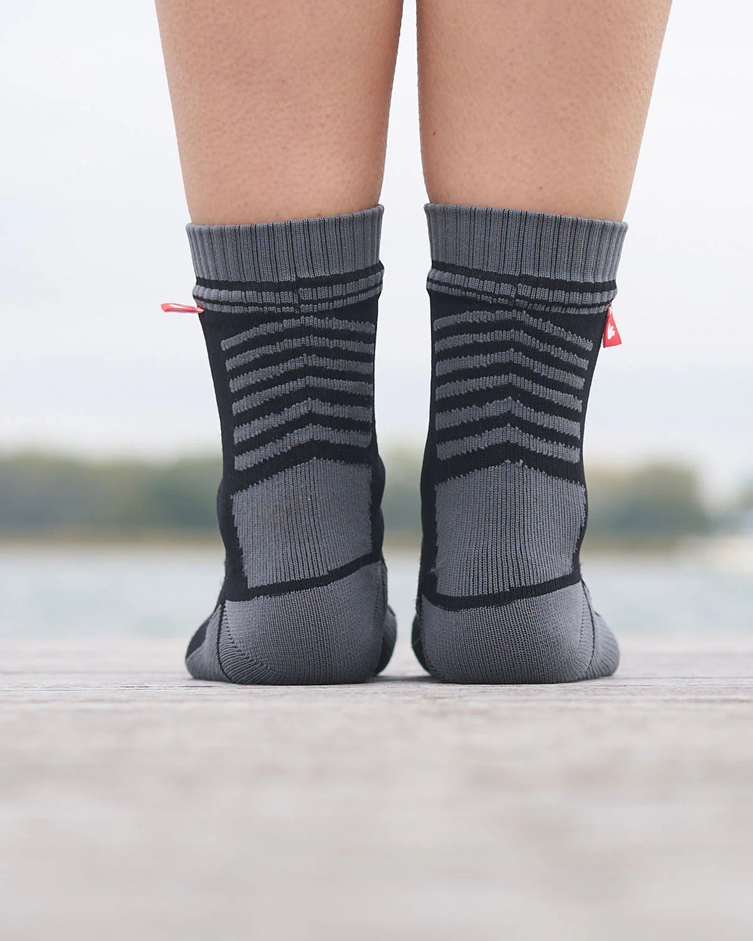 Gray waterproof socks with black stripes worn by a person on a blurred background.