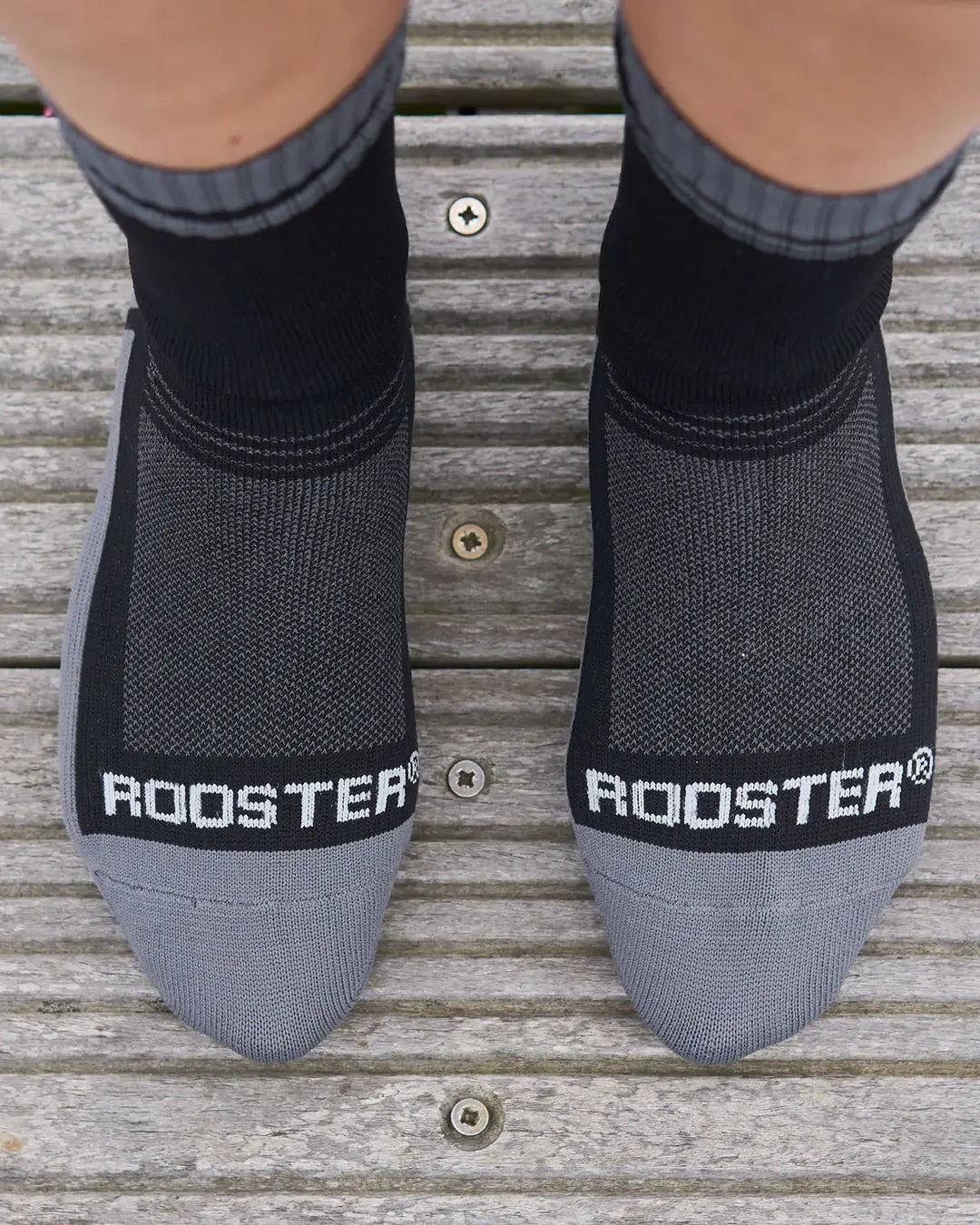 Black and grey waterproof socks with 'Rooster' branding on a wooden floor.