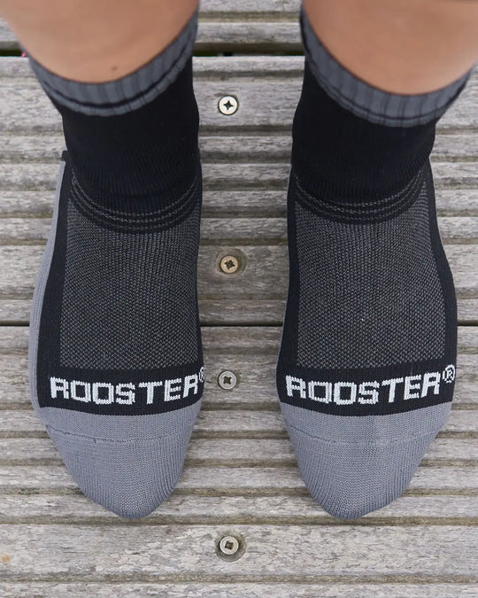 Black and grey waterproof socks with 'Rooster' branding on a wooden floor.