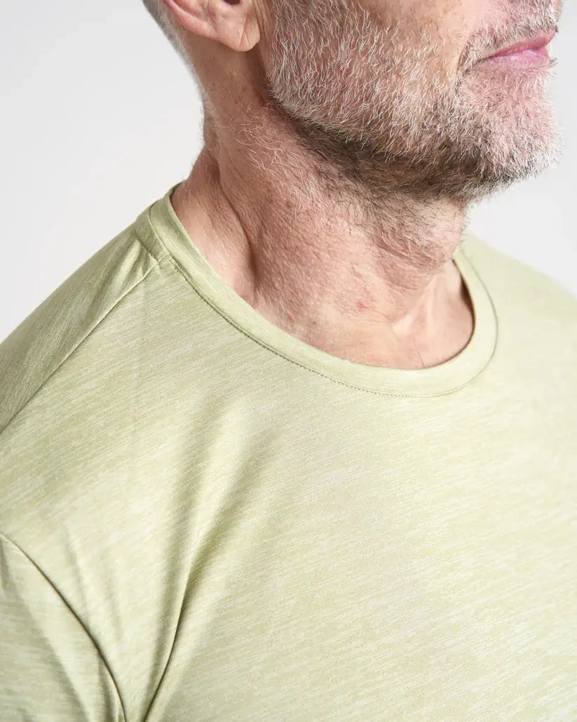 Close-up of a person wearing a light khaki t-shirt against a plain background.