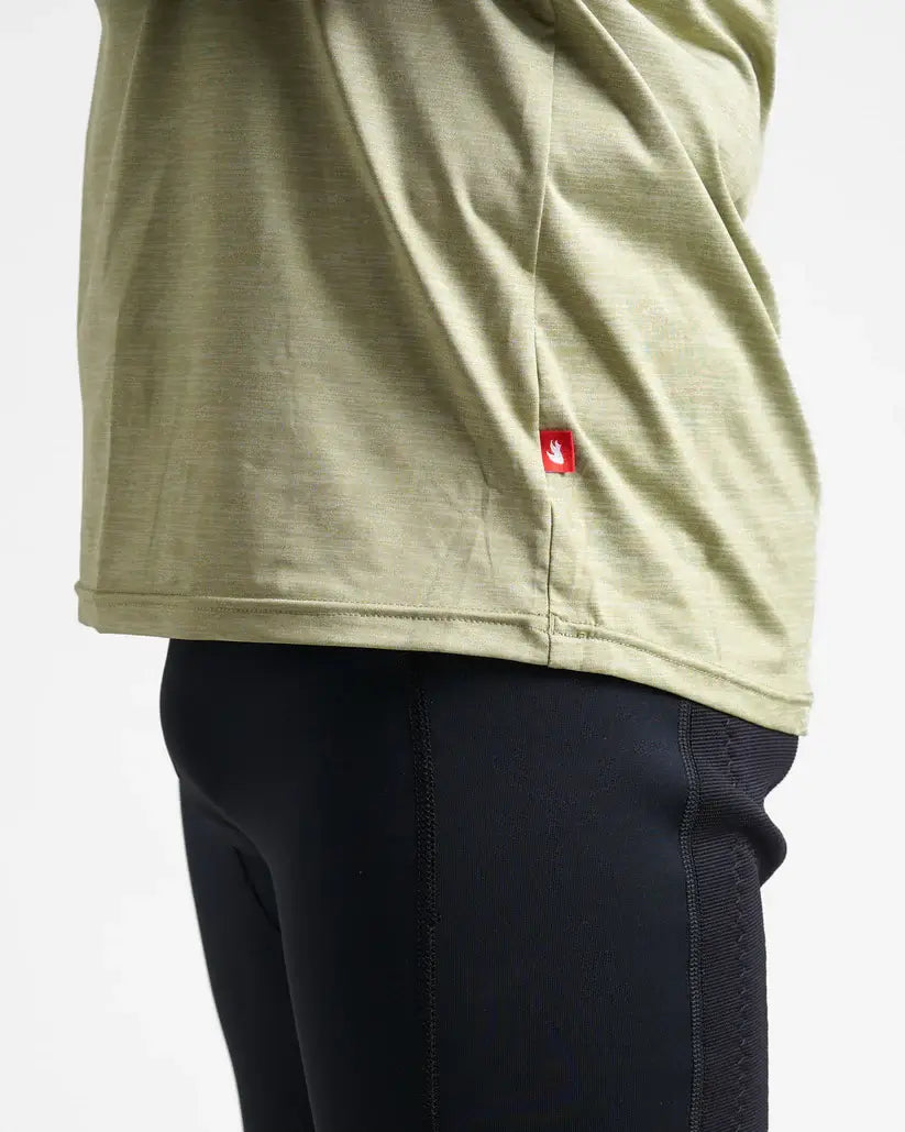 Person wearing a khaki quick dry t-shirt with a red logo and dark pants on a white background.