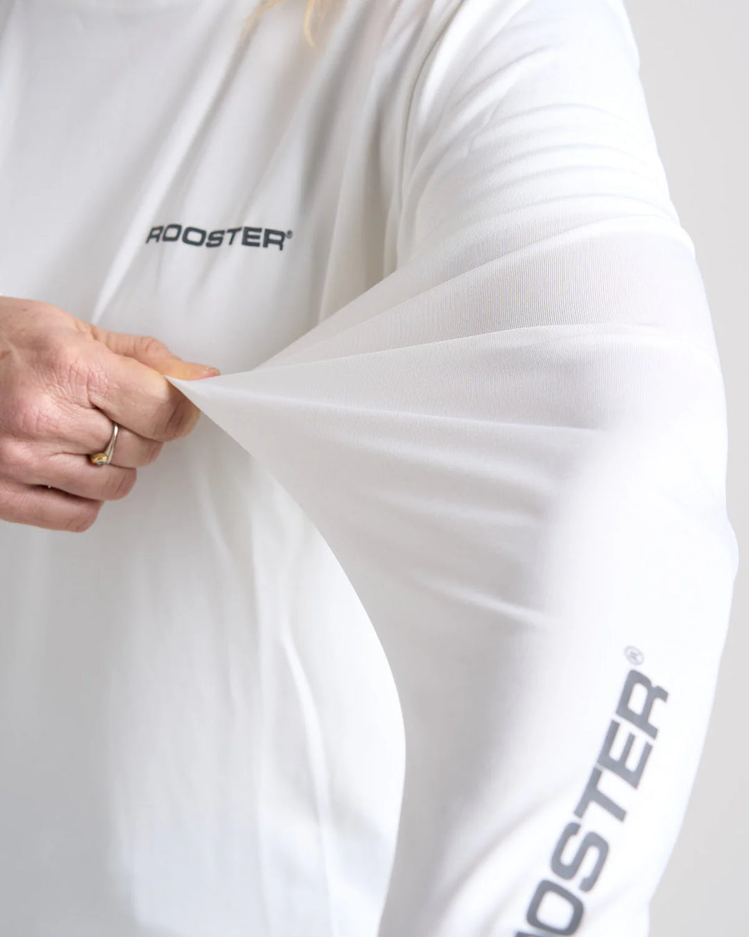White garment with 'Rooster' branding being held by a person.