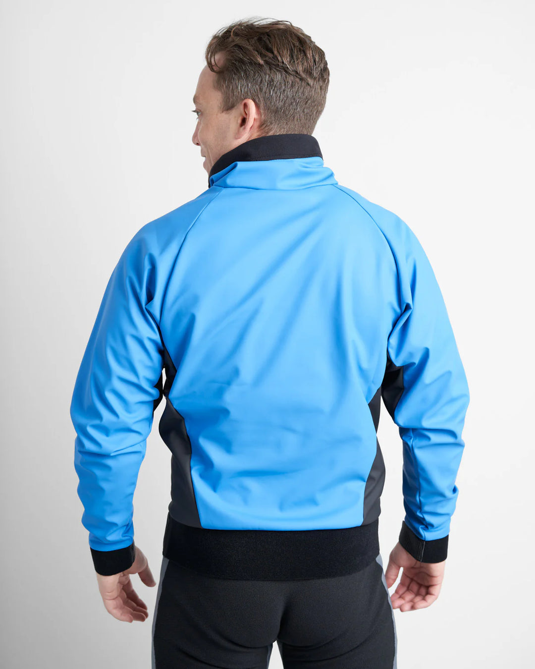 Person wearing a blue and black dinghy sailing spray top on a white background.