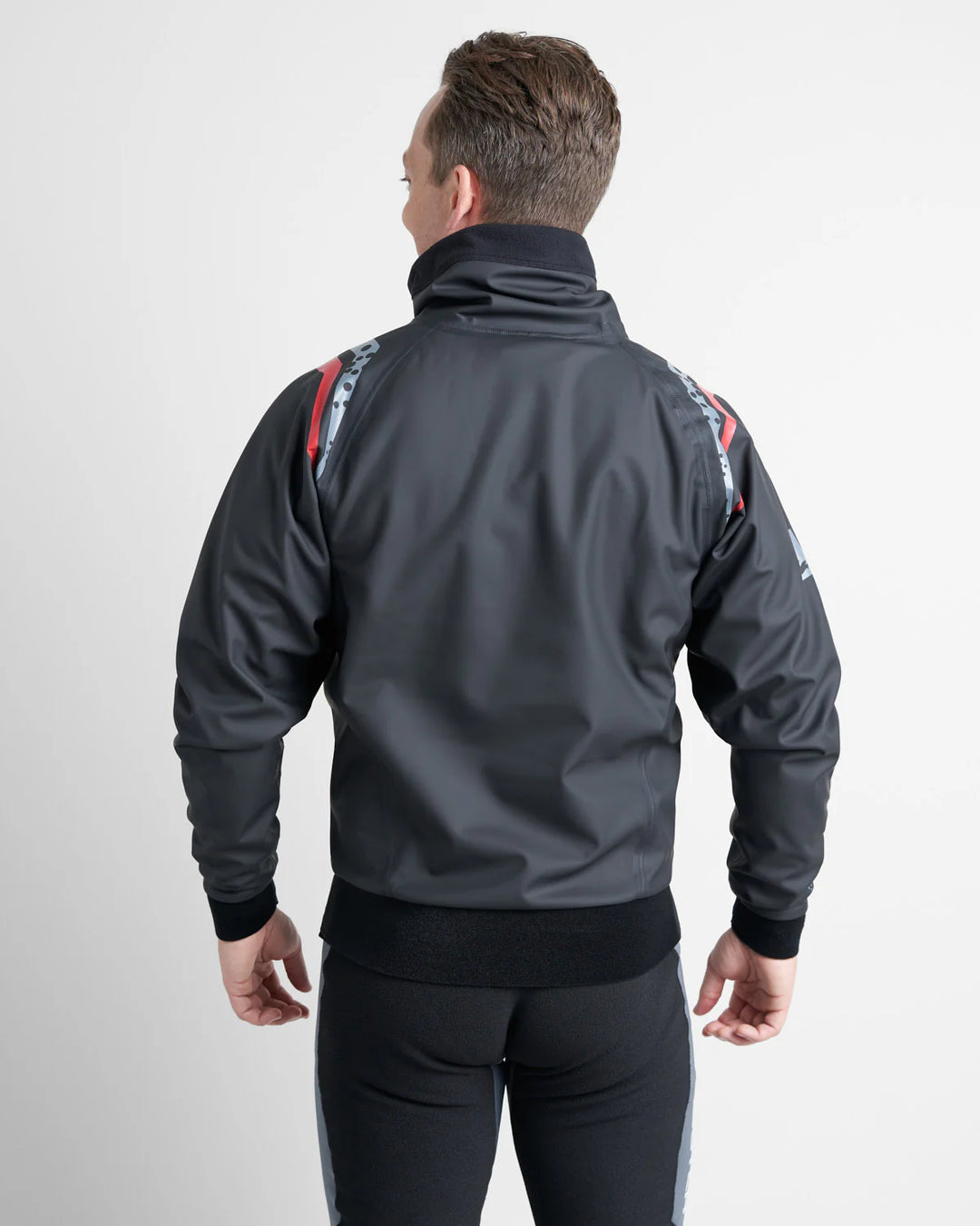 Man wearing a black dinghy sailing spray top with colourful designs on the back against a white background.