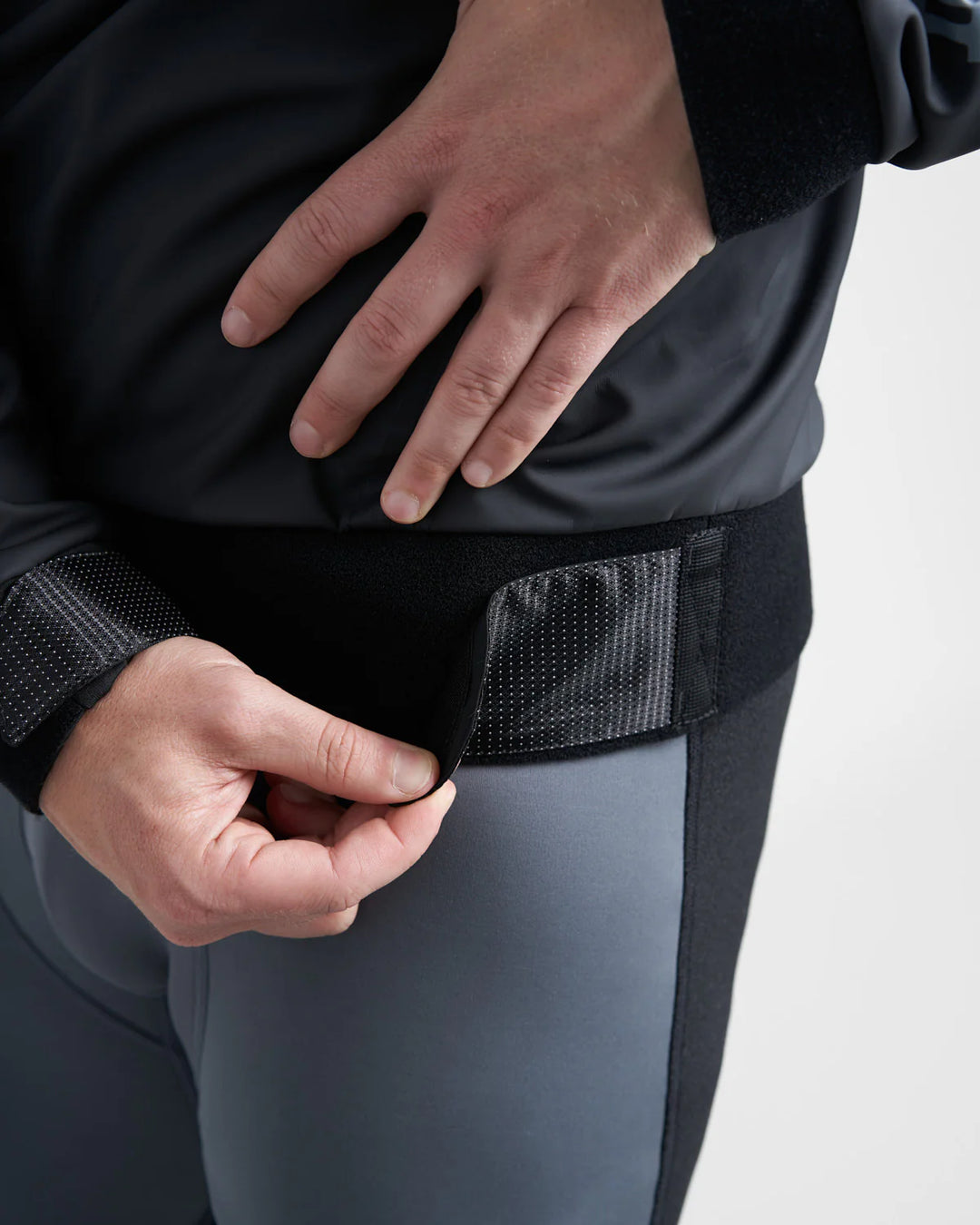 Person adjusting a black waistband on a black Rooster Aquafleece Pro Sailing Top against a white background.