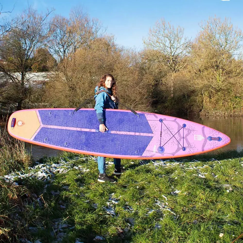 Female paddleboarder using the shoulder carry strap on the purple Shark SUPs Roam Travel SUP.