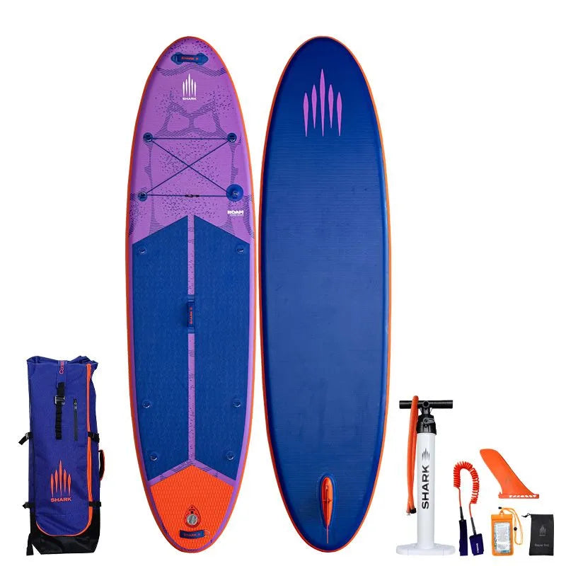 Image of Shark SUPS Roam 10'6 x 32" x 5" inflatable travel paddle board with light purple deck featuring shark skin graphics and a dark blue bottom. Also showing package accessories.