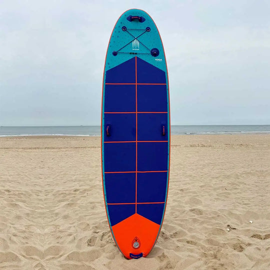 Shark SUPS Yoga Paddleboard in teal with blue deck pad and orange kick tail, stood up on the beach.