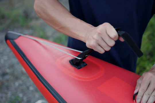 Person holding the Quick Tension System handle on a Starboard All Star Airline Inflatable Paddleboard against a blurred natural background.