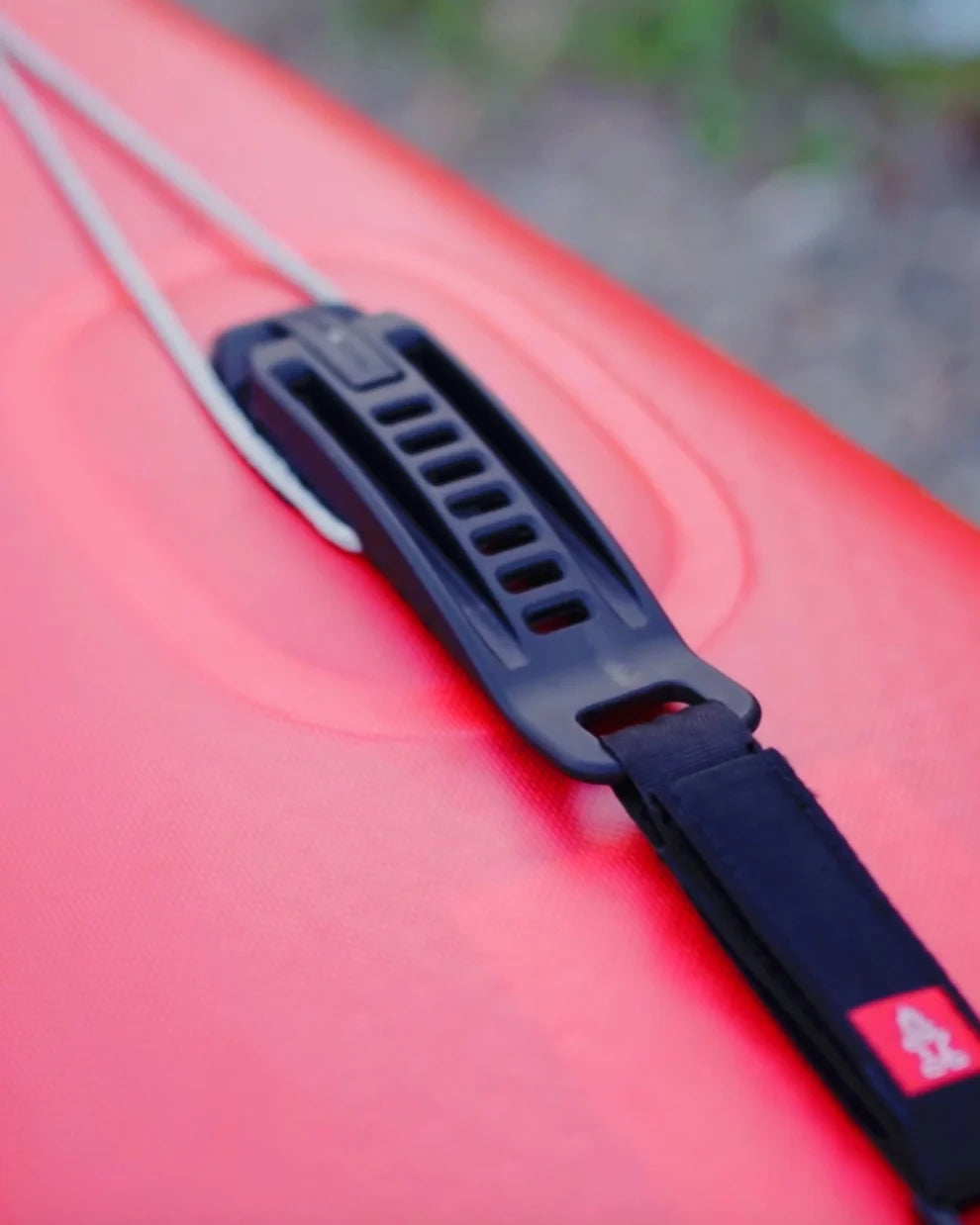 Close up of the red nose of the Starboard All Star Airline Inflatable Paddleboard with the black handle of the quick tension system.