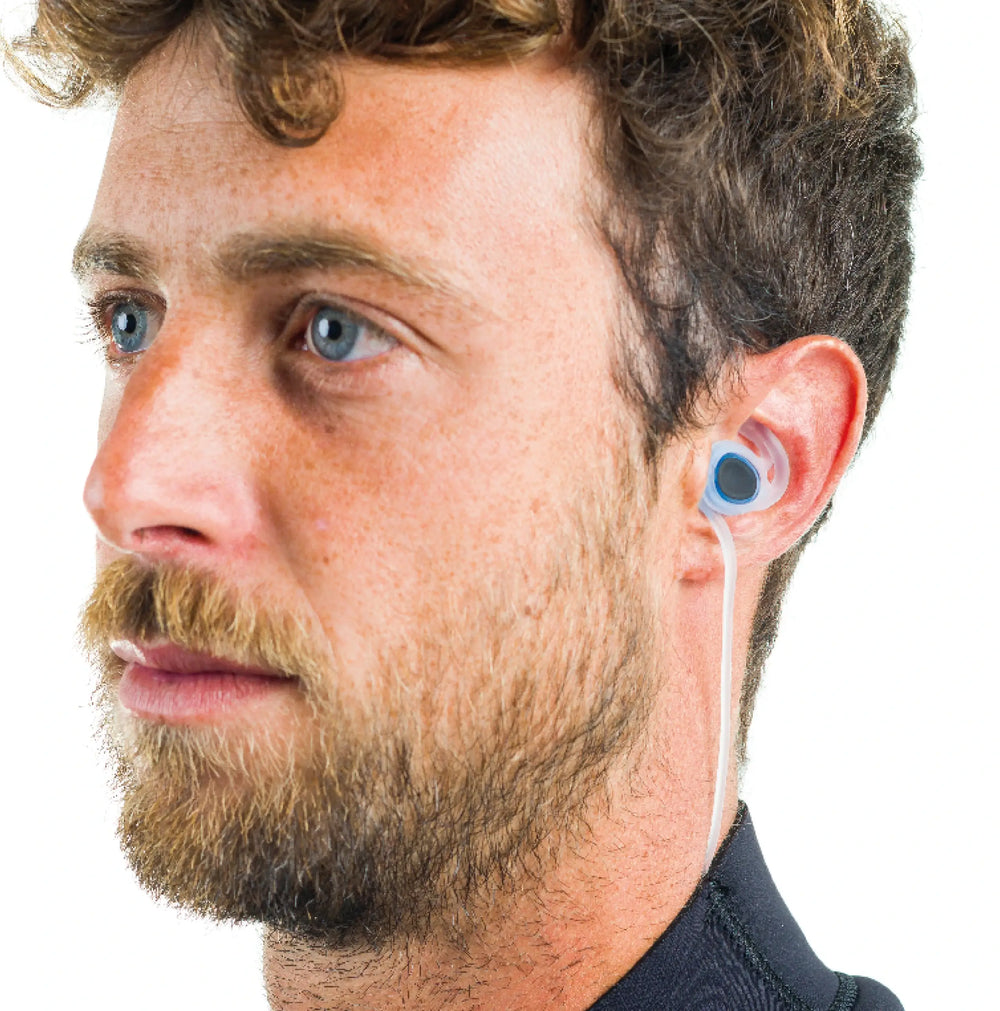Man wearing blue Surflogic surfing earplugs in his ear with a white background.